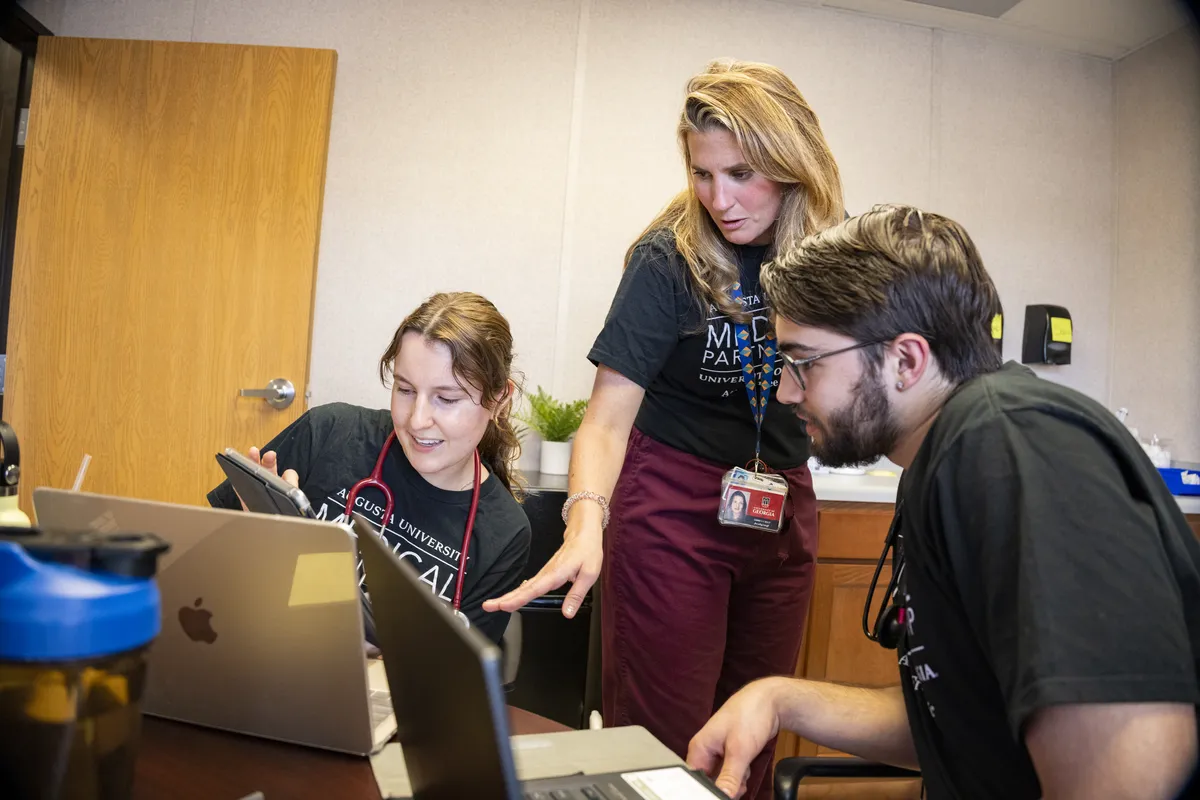 UGA employees working together on a laptop.