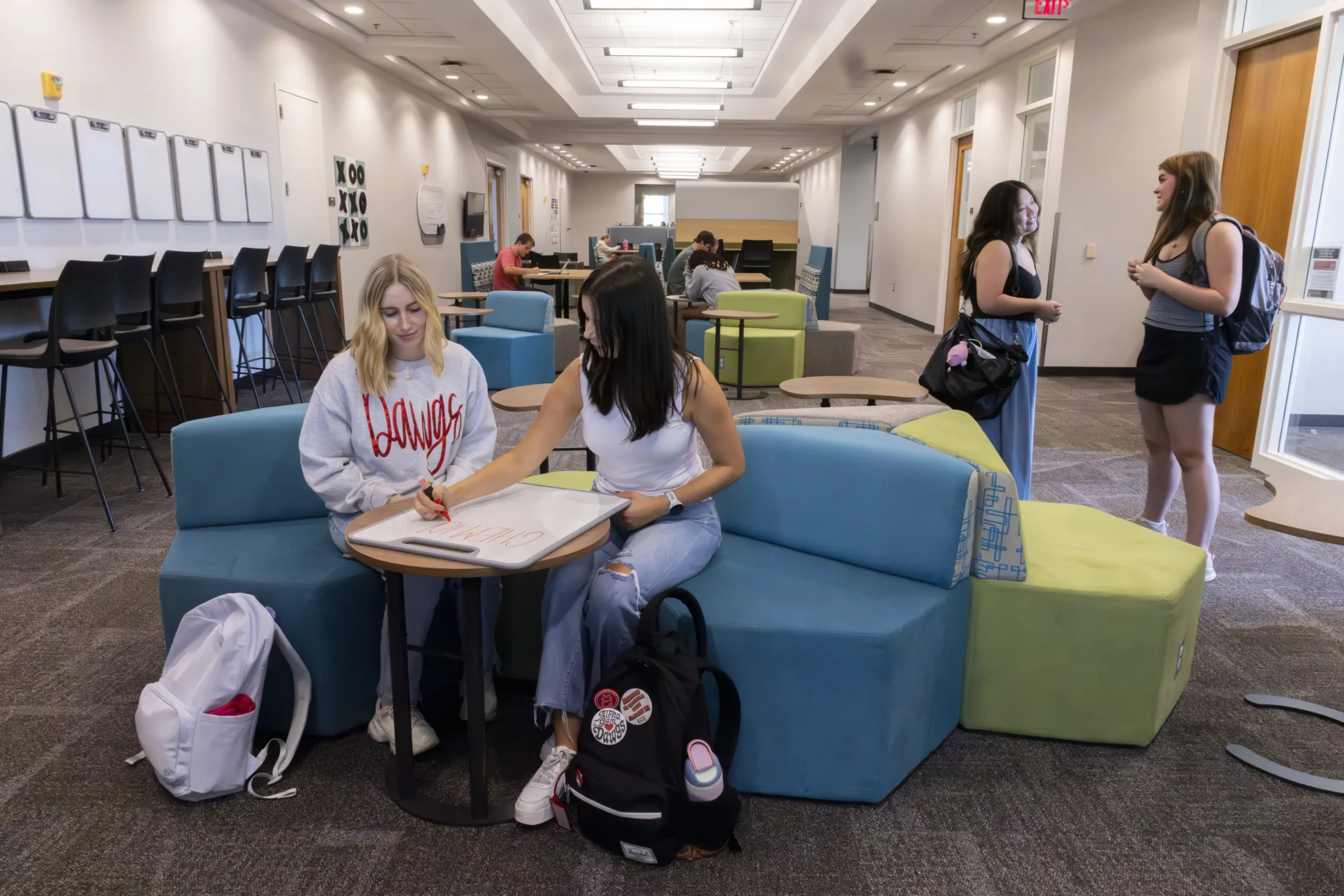 Students study and chat on colorful lounge seating in a campus learning space